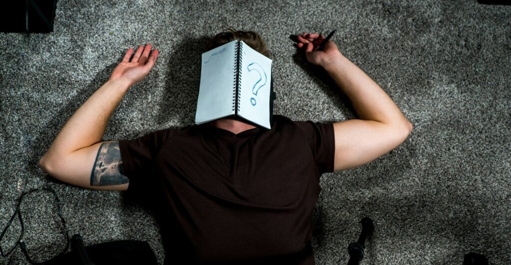 Person lying on the floor with a notebook over their face, illustrating feeling stuck when coming up with brand storytelling ideas.