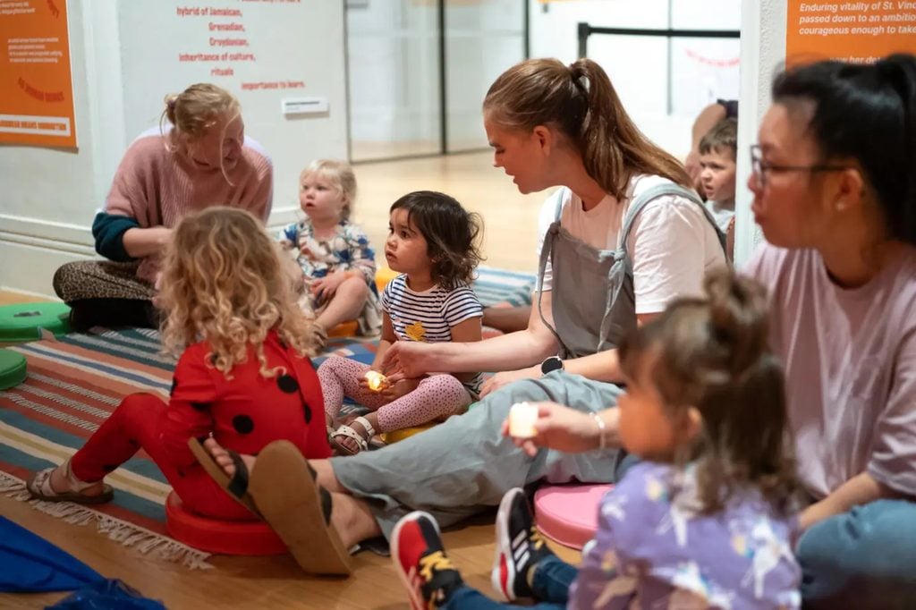 Toddlers holding candles during a Little Explorers session at the National Portrait Gallery, one of many things to do with kids in London